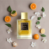 A'LALÓRE marka kadın parfümü 100 ml şişesi ve etrafında portakal dilimleri ile beyaz çiçekler